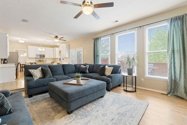 14263 W 129th Ter, Olathe, KS 66062 - living area featuring a ceiling fan, healthy amount of natural light, light wood-type flooring, baseboards, and a textured ceiling