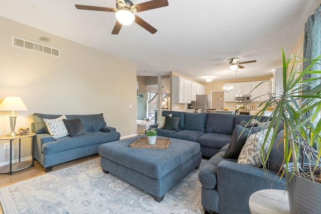 14263 W 129th Ter, Olathe, KS 66062 - living area featuring a ceiling fan, baseboards, light wood finished floors, and stairway