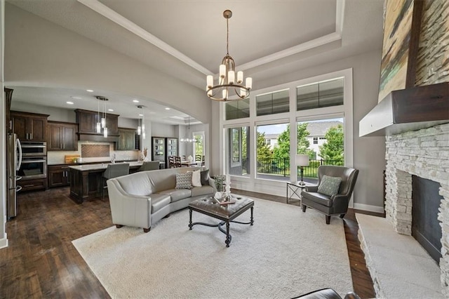16456 Cody St, Overland Park, KS 66062 - living area with a fireplace, a raised ceiling, a chandelier, dark wood-style flooring, and arched walkways