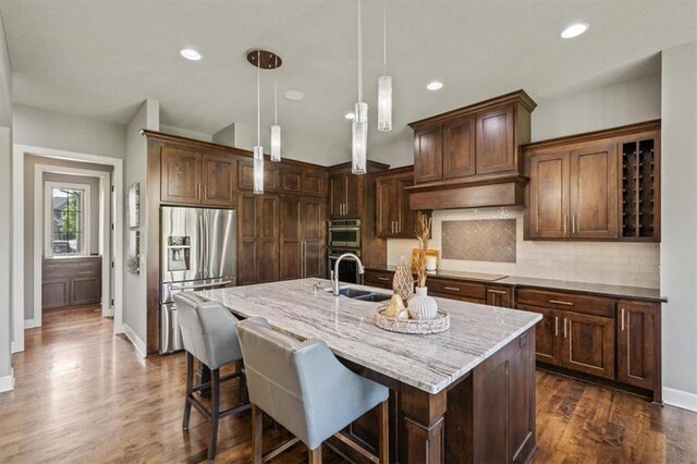 16456 Cody St, Overland Park, KS 66062 - kitchen with stainless steel appliances, a sink, tasteful backsplash, light stone counters, and an island with sink