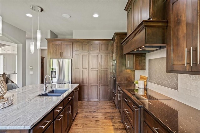 16456 Cody St, Overland Park, KS 66062 - kitchen featuring appliances with stainless steel finishes, a sink, light stone counters, hanging light fixtures, and wood finished floors