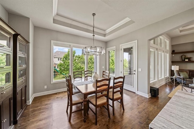 16456 Cody St, Overland Park, KS 66062 - dining area with a chandelier, dark wood-type flooring, a raised ceiling, and baseboards