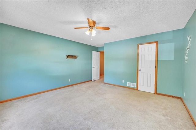 unfurnished room with ceiling fan, carpet flooring, baseboards, and a textured ceiling