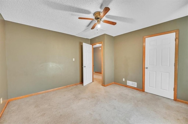 unfurnished bedroom featuring carpet floors, baseboards, a textured ceiling, and ceiling fan