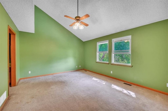 carpeted empty room with a textured ceiling, a ceiling fan, vaulted ceiling, and baseboards