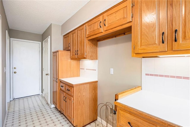 7001 W 157th Ter, Overland Park, KS 66223 - kitchen featuring light countertops, tasteful backsplash, brown cabinets, a textured ceiling, and light flooring