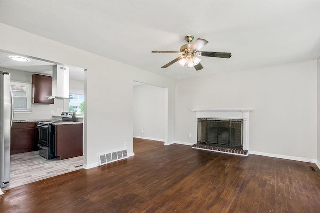 1924 N 75th Dr, Kansas City, KS 66112 - unfurnished living room featuring a ceiling fan, wood finished floors, baseboards, and a brick fireplace
