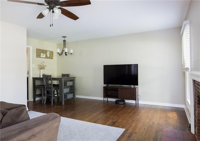 living area featuring a chandelier, wood finished floors, a ceiling fan, and baseboards