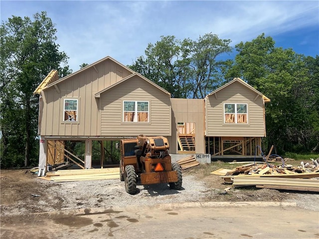 rear view of house featuring board and batten siding and stairway