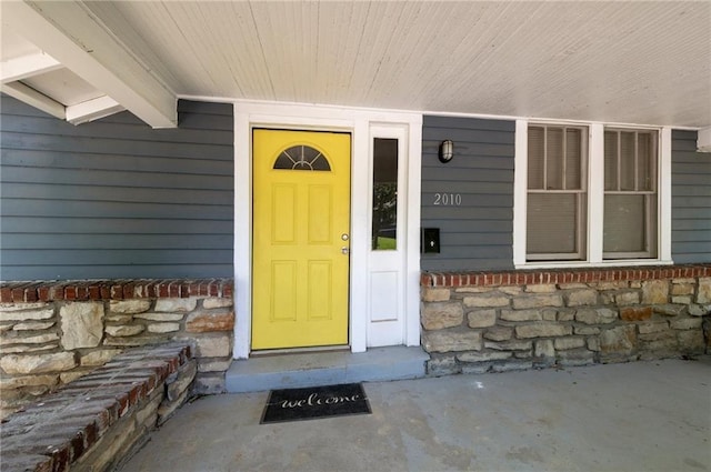 entrance to property featuring stone siding and covered porch