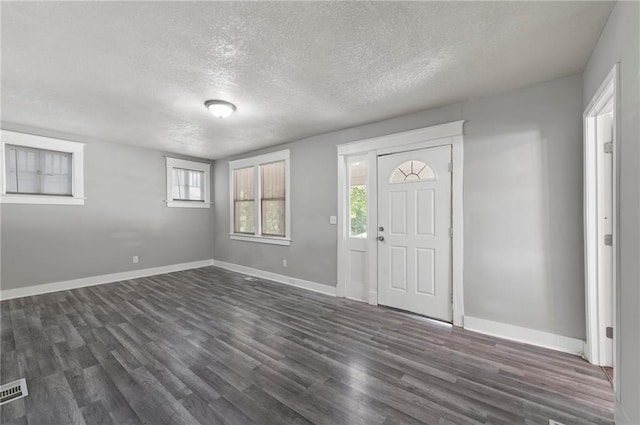 foyer featuring dark wood-style flooring, a textured ceiling, and baseboards