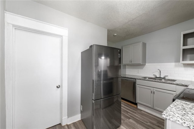 kitchen with stainless steel appliances, a sink, dark wood finished floors, a textured ceiling, and gray cabinetry
