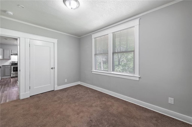 empty room with dark carpet, ornamental molding, a textured ceiling, a smoke detector, and baseboards