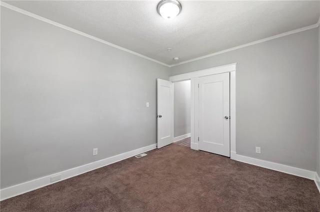 unfurnished bedroom with ornamental molding, dark colored carpet, baseboards, and a textured ceiling
