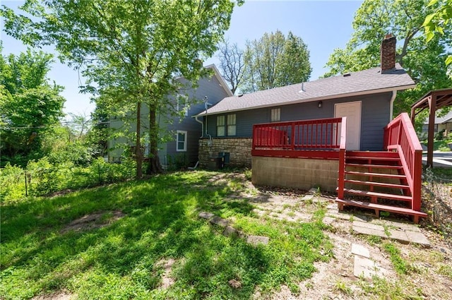 rear view of house featuring a deck, a chimney, and stone siding