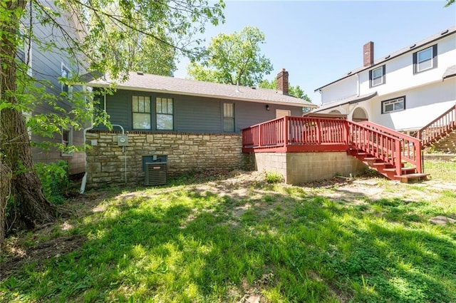 rear view of property with stone siding, a deck, stairs, a chimney, and a yard