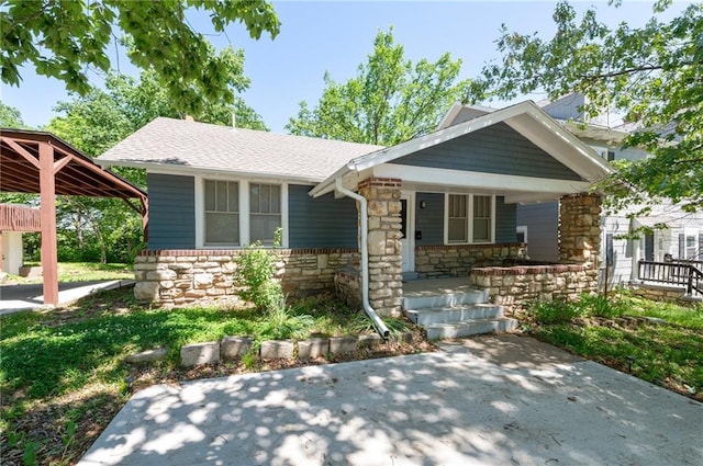 view of front of home with stone siding, a porch, and a shingled roof