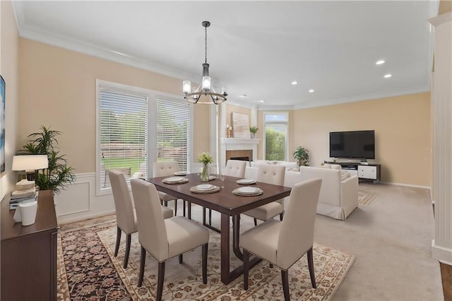 dining area with crown molding, a chandelier, recessed lighting, a tiled fireplace, and light carpet