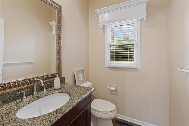 bathroom with toilet, vanity, and baseboards