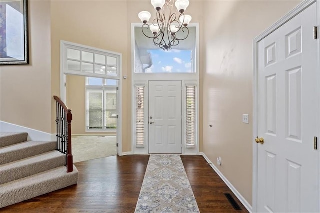 foyer featuring a chandelier, dark wood-type flooring, stairway, a high ceiling, and baseboards