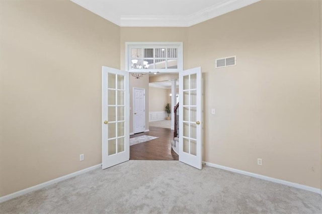 empty room with french doors, carpet flooring, baseboards, crown molding, and a high ceiling