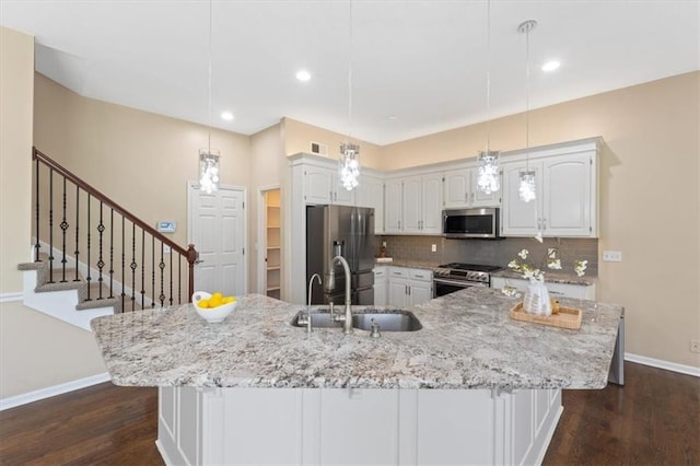 kitchen featuring appliances with stainless steel finishes, a sink, baseboards, white cabinetry, and dark wood finished floors