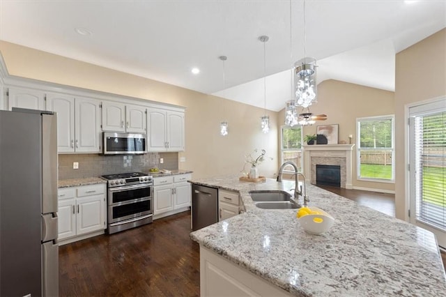 kitchen featuring stainless steel appliances, a sink, backsplash, lofted ceiling, and a large island