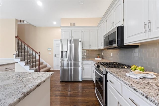 kitchen featuring appliances with stainless steel finishes, dark wood-style floors, white cabinetry, light stone countertops, and recessed lighting
