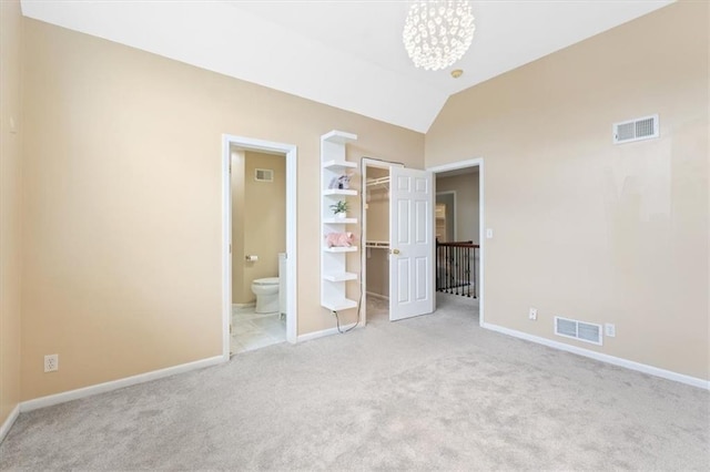 unfurnished bedroom with carpet, a walk in closet, baseboards, vaulted ceiling, and ensuite bathroom