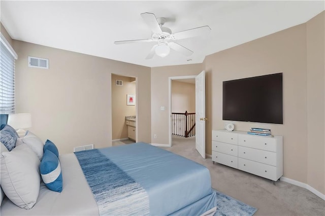 bedroom featuring light colored carpet, baseboards, ceiling fan, and ensuite bathroom