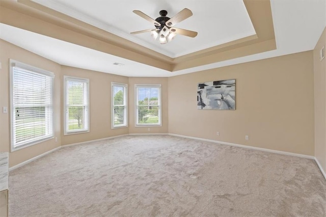 carpeted spare room with a tray ceiling, a ceiling fan, and baseboards
