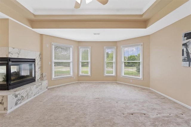 unfurnished living room with carpet floors, baseboards, crown molding, and a high end fireplace