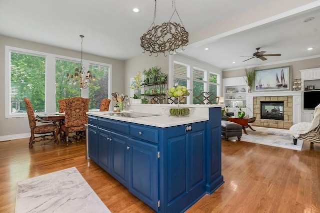 6104 W 144th St, Overland Park, KS 66223 - kitchen with blue cabinets, a chandelier, a multi sided fireplace, light countertops, and recessed lighting