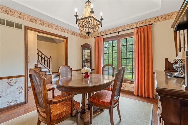 20129 W 112th Cir, Olathe, KS 66061 - dining area featuring wood finished floors, a chandelier, stairs, baseboards, and wallpapered walls