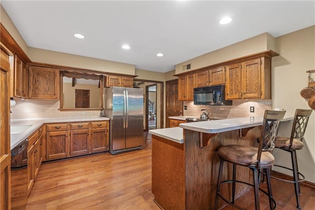 20129 W 112th Cir, Olathe, KS 66061 - kitchen featuring black appliances, a peninsula, brown cabinets, backsplash, and recessed lighting