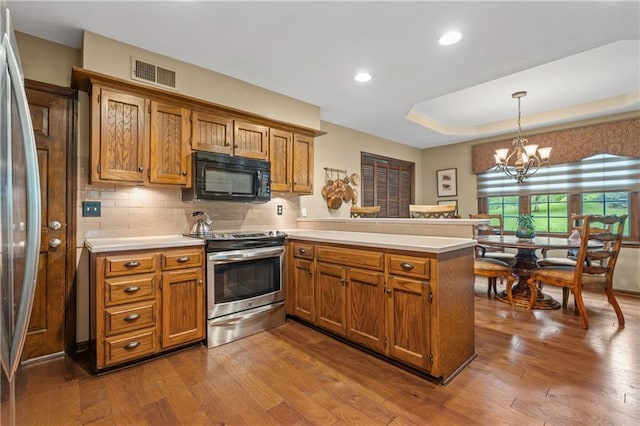 20129 W 112th Cir, Olathe, KS 66061 - kitchen with stainless steel appliances, a peninsula, brown cabinetry, dark wood finished floors, and recessed lighting