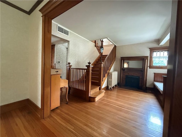 1701 Main St, Lexington, MO 64067 - unfurnished living room with radiator, wood finished floors, a fireplace, and stairs