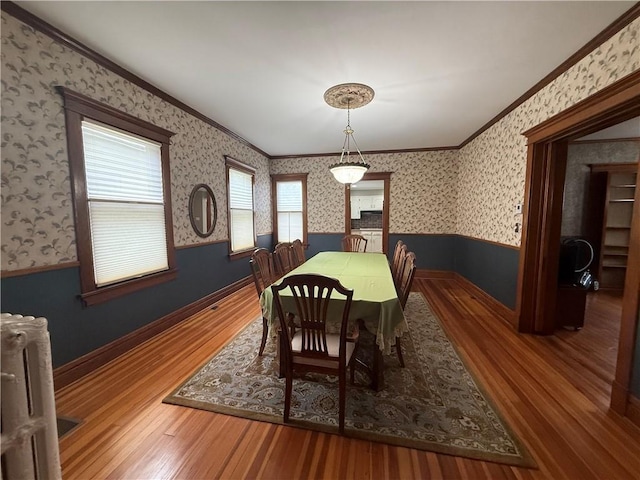 1701 Main St, Lexington, MO 64067 - dining room featuring wainscoting, wood finished floors, ornamental molding, radiator, and wallpapered walls
