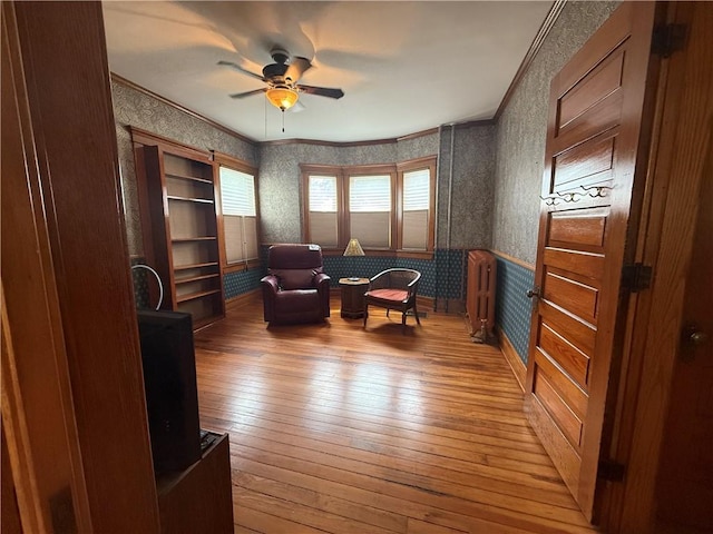 1701 Main St, Lexington, MO 64067 - sitting room featuring wallpapered walls, light wood finished floors, a ceiling fan, a wainscoted wall, and ornamental molding