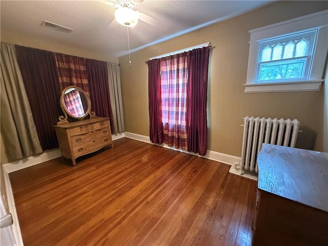 1701 Main St, Lexington, MO 64067 - unfurnished bedroom featuring radiator heating unit, hardwood / wood-style floors, a textured ceiling, and ceiling fan
