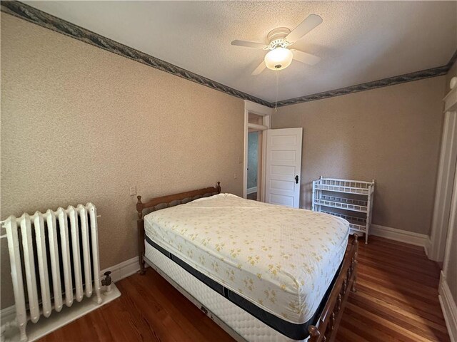 1701 Main St, Lexington, MO 64067 - bedroom featuring radiator, dark wood-type flooring, a textured ceiling, a ceiling fan, and a textured wall
