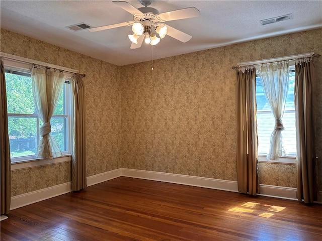 1701 Main St, Lexington, MO 64067 - empty room featuring dark wood finished floors, healthy amount of natural light, ceiling fan, a textured ceiling, and wallpapered walls