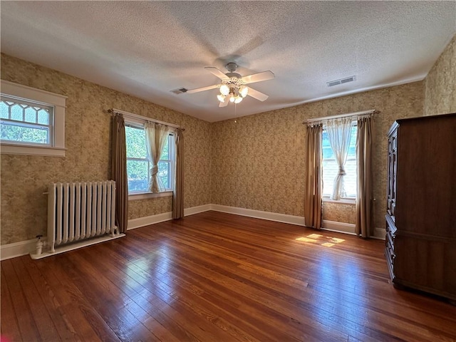 1701 Main St, Lexington, MO 64067 - empty room featuring radiator heating unit, hardwood / wood-style floors, healthy amount of natural light, a textured ceiling, and a ceiling fan