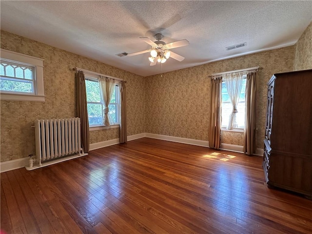 1701 Main St, Lexington, MO 64067 - unfurnished room with radiator heating unit, hardwood / wood-style flooring, plenty of natural light, a textured ceiling, and wallpapered walls