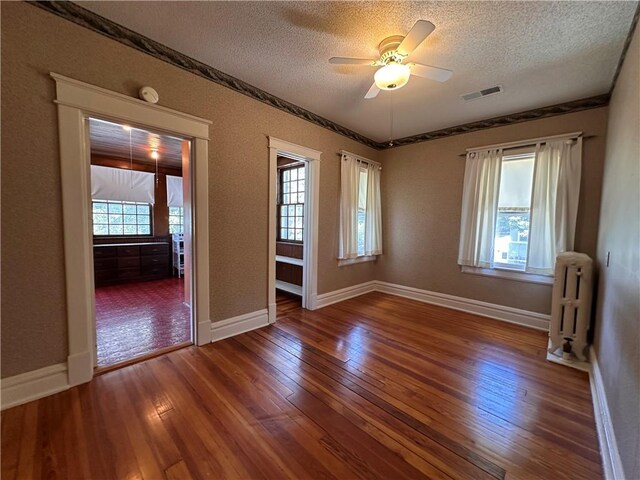 1701 Main St, Lexington, MO 64067 - unfurnished room with a textured ceiling, radiator, hardwood / wood-style floors, ceiling fan, and a smoke detector