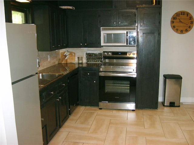 509 Pearl St, Pittsburg, KS 66762 - kitchen with stainless steel appliances, dark countertops, decorative backsplash, baseboards, and light tile patterned floors