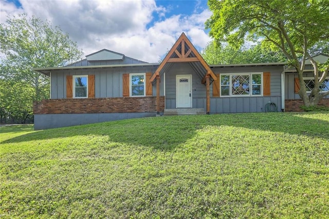 view of front of home with a front yard, board and batten siding, and brick siding