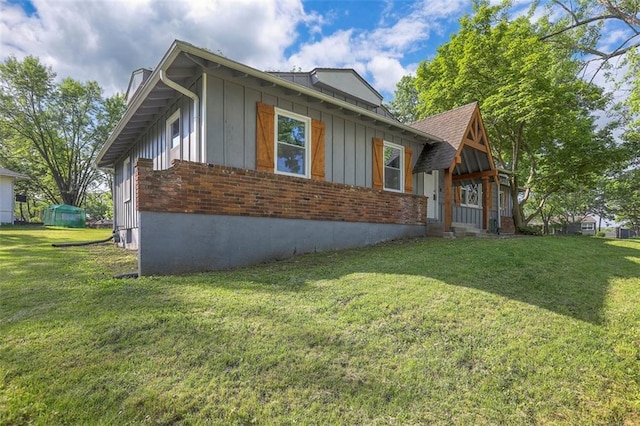 view of home's exterior with board and batten siding, a lawn, and brick siding