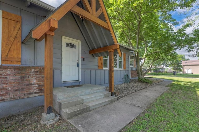doorway to property featuring brick siding and a yard
