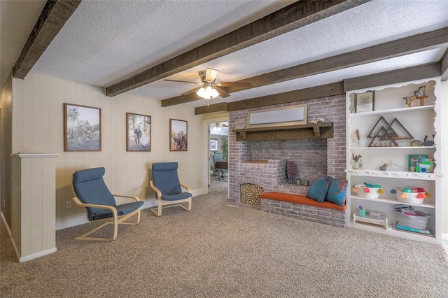 carpeted living room featuring a fireplace, a textured ceiling, beamed ceiling, a ceiling fan, and baseboards